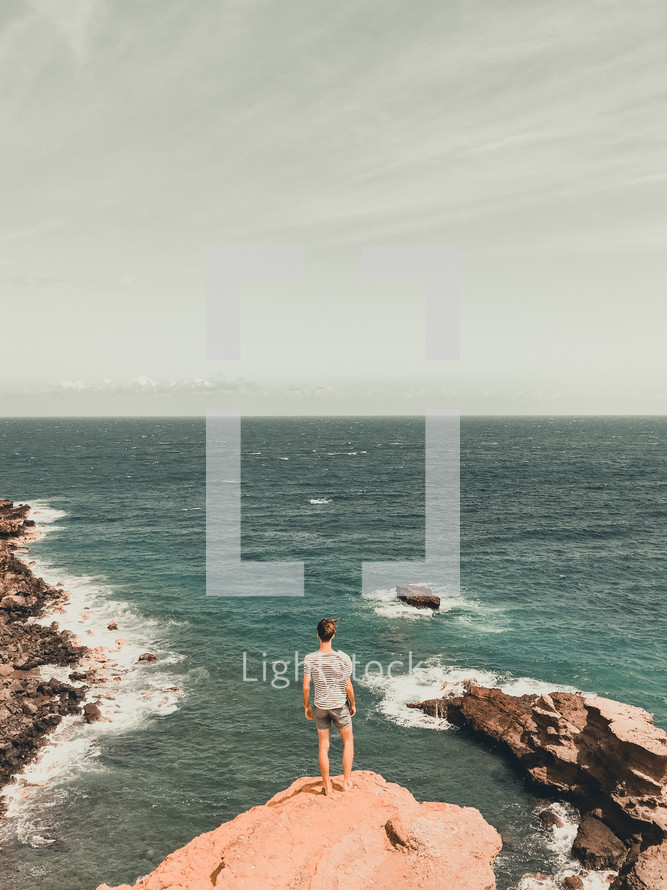 woman standing at the edge of a cliff overlooking the ocean 