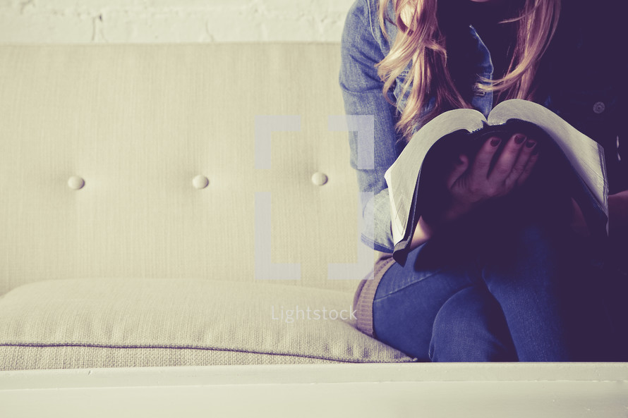 woman sitting on a couch reading a Bible