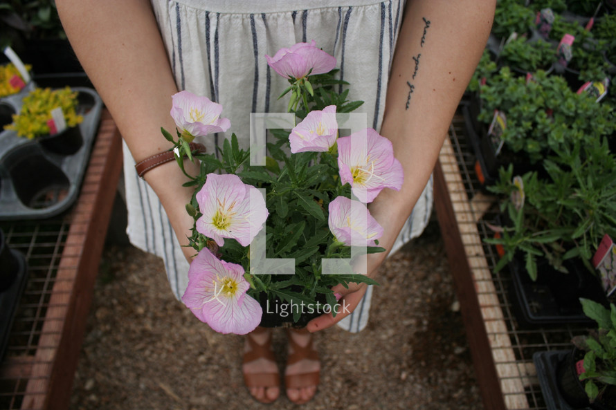 a woman holding flowers in a garden center 
