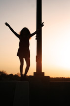silhouette of a woman with arms raised at sunset 