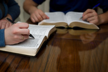 two men at a Bible study with their pens on a Bible