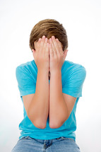 teen boy covering his face