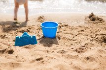 Feet and sand toys at the beach.