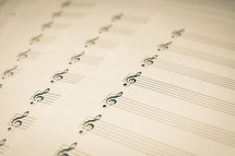 Sheets of empty music manuscript paper with a treble clef on the staff, in black & white (b&w) sepia.