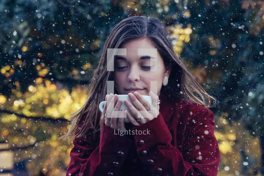 a teen girl drinking from a mug in the snow 
