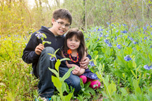 Young boy and small girl, sitting among wild flowers