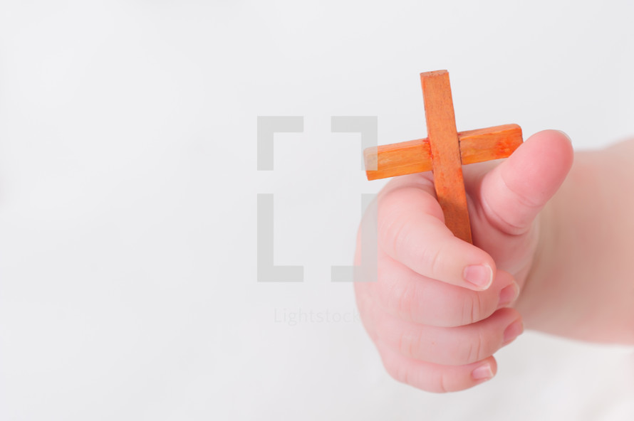 Infant's hand holding a small wooden cross