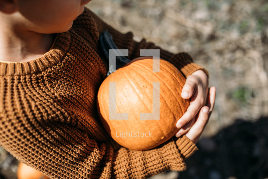 child holding a pumpkin 