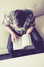 man sitting on a couch reading a Bible