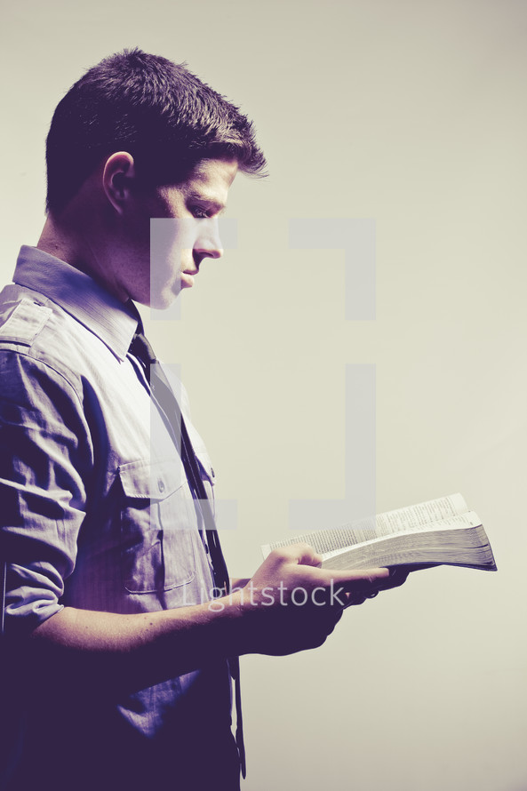 man reading a Bible against a white background