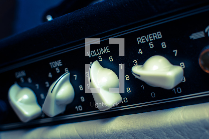 Guitar amplifier level dials: tone, gain, volume & reverb in cross-processed look.
