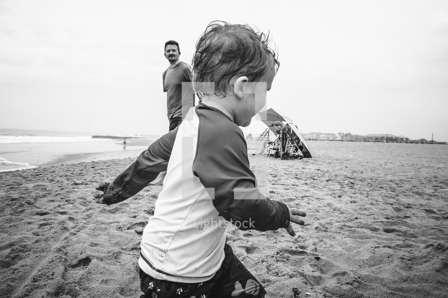 father and toddler son playing on a beach 