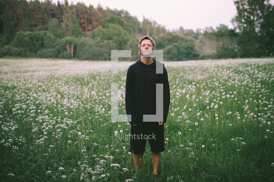 A young man standing in a field of wild flowers 
