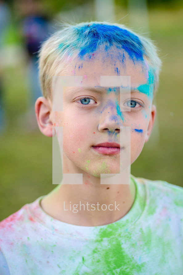 a boy with a colorful face after a color run 