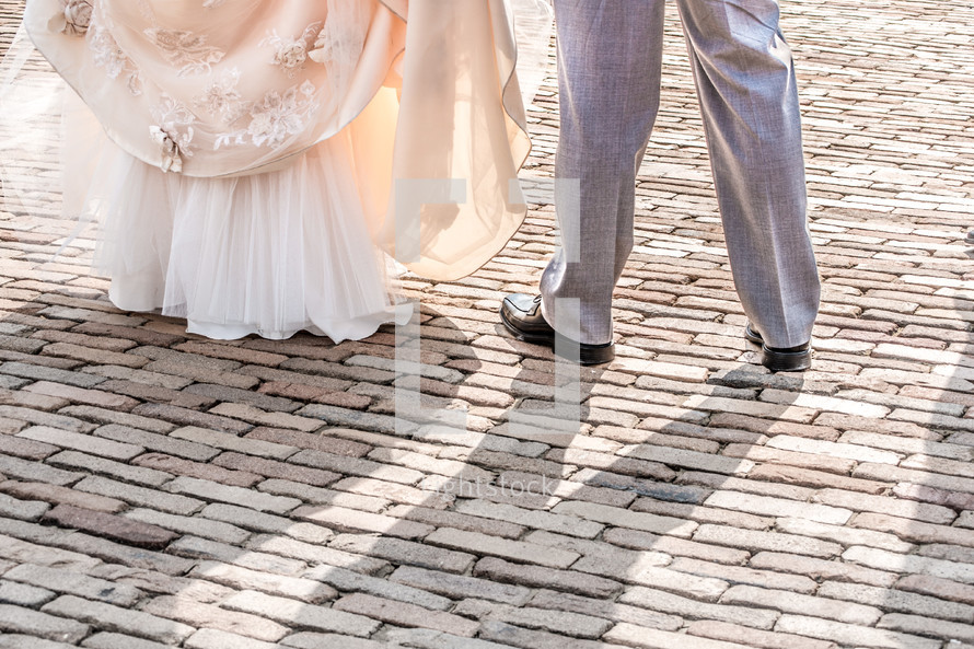 feet of a bride and groom dancing on brick pavers 