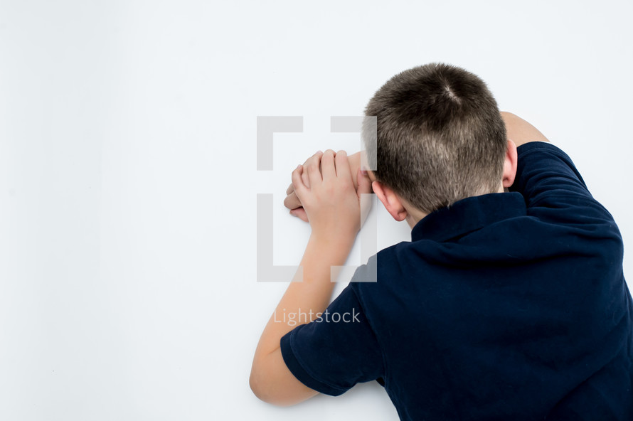 Child with his head on his arm, face down.