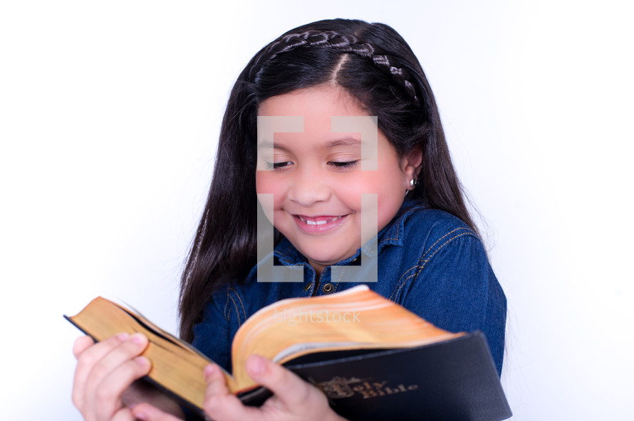 Smiling girl reading the Bible.
