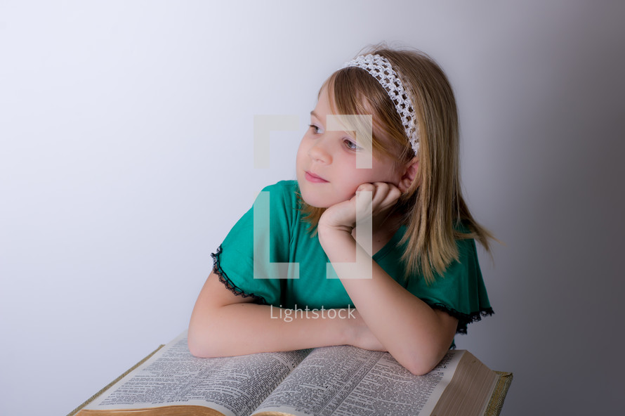 Girl thinking over the Bible.