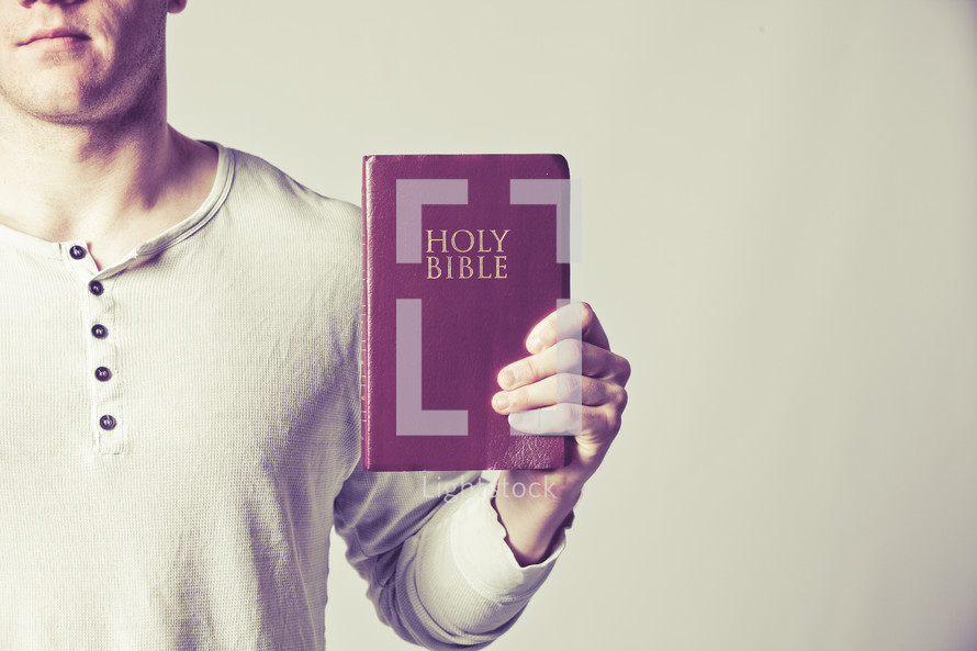 man holding out a red covered Holy Bible