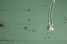 earbuds laying on a an old green table. 