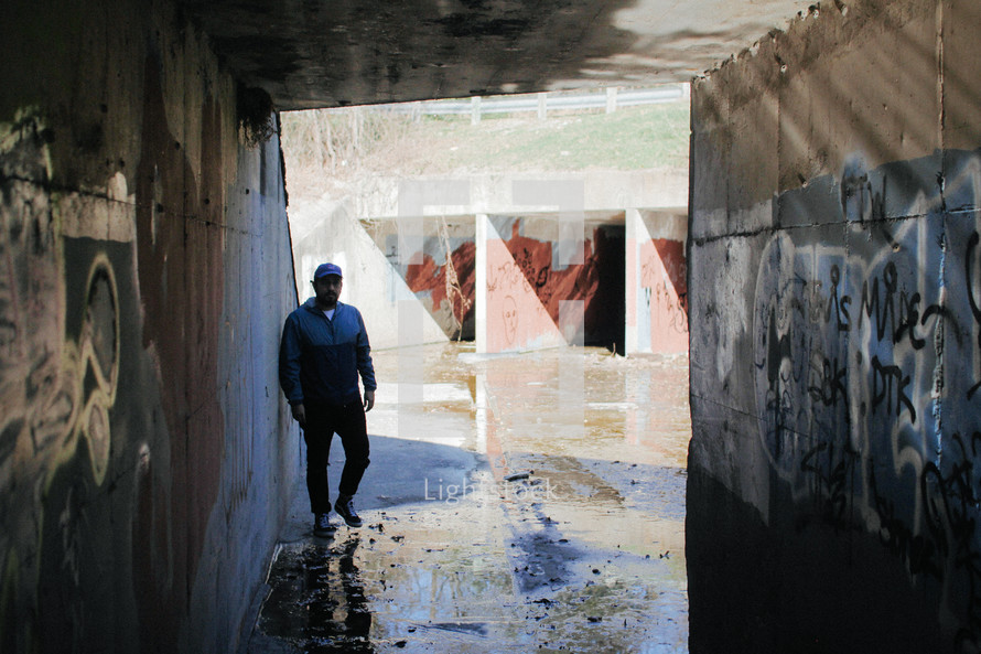 man standing under a concrete tunnel 