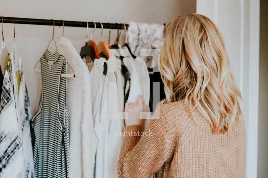 a woman looking at clothes in her closet 