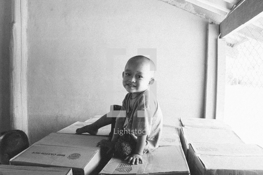 a smiling young boy sitting on boxes 