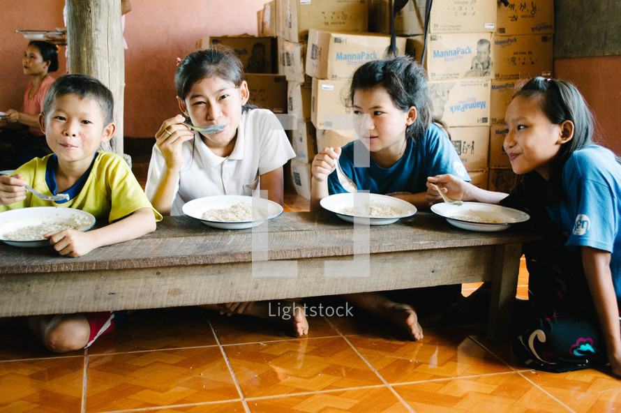 children in an orphanage eating in a cafeteria 