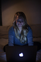 young woman looking at her computer screen in a dark room 