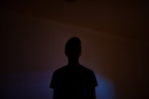 silhouette of a young man in a dark room 
