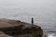 a person standing on a rocky shore in Maine 