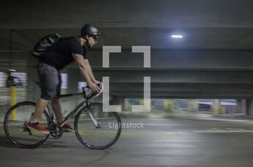 a man riding a bicycle in a parking garage 