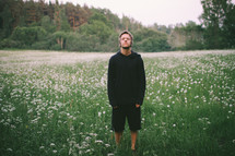A young man standing in a field of wild flowers 