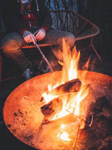 A man sits beside a bonfire.