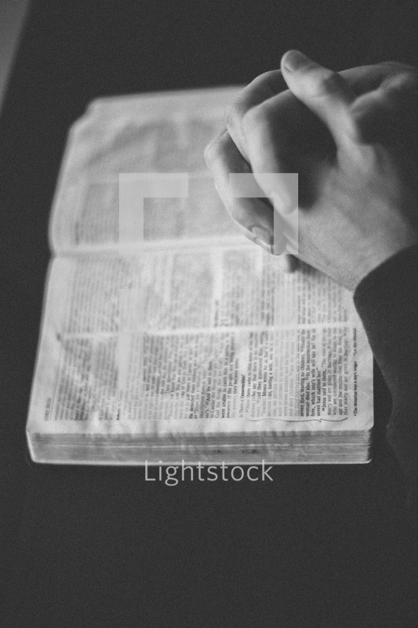 prayer hands held over a Bible