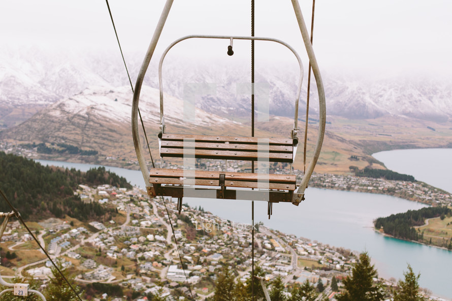 An empty ski lift chair in the air above a town. — Photo