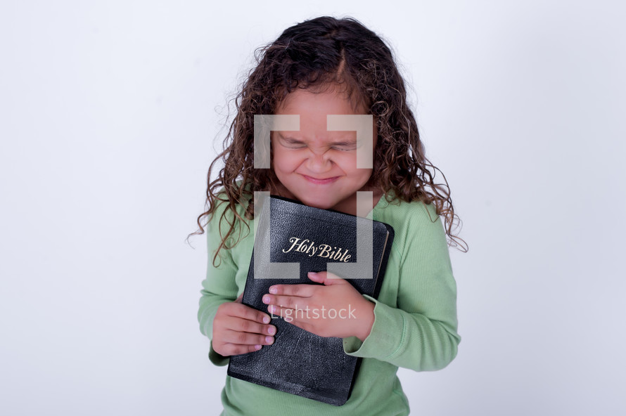 Girl squeezing a closed Bible.