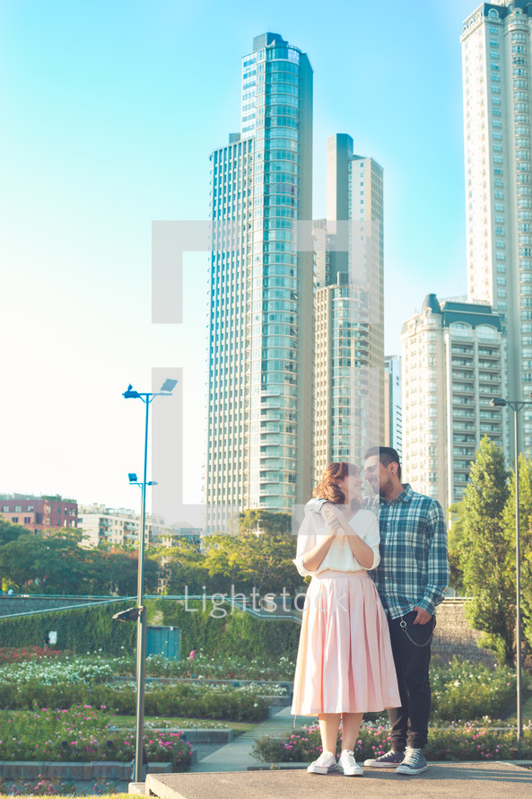 a couple standing together in front of a city 