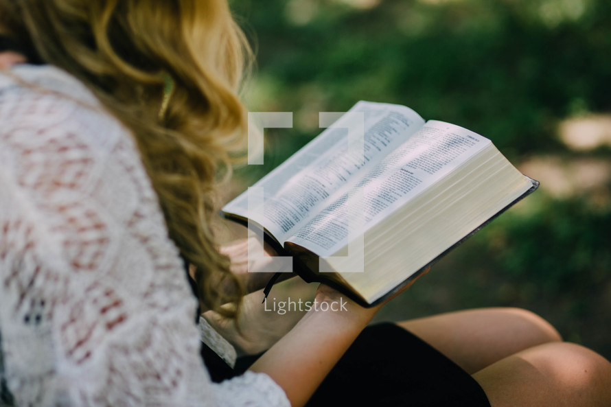 A woman reading a Bible outdoors 