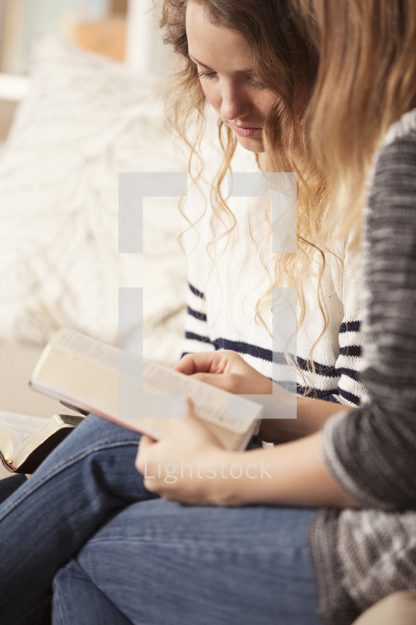 Friends sitting on the sofa together reading the Bible.