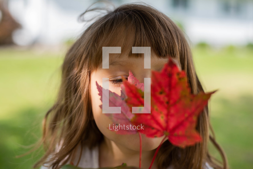 girl holding a red fall leaf 