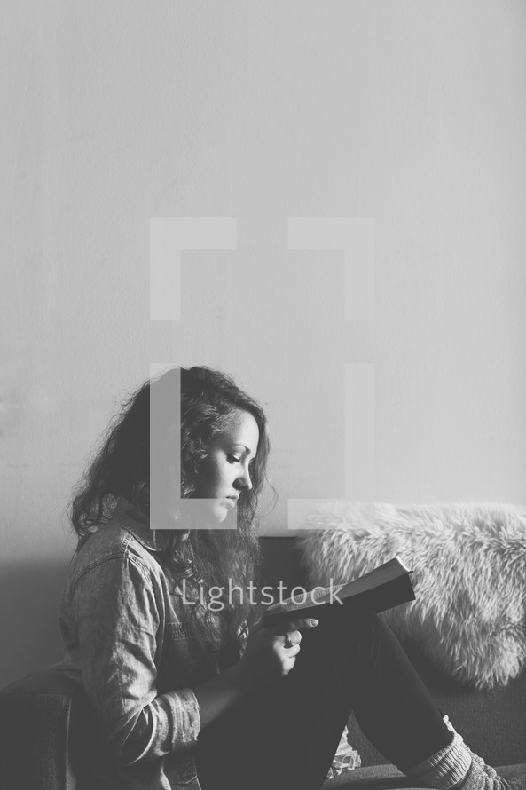 Woman sitting on a sofa reading the Bible.