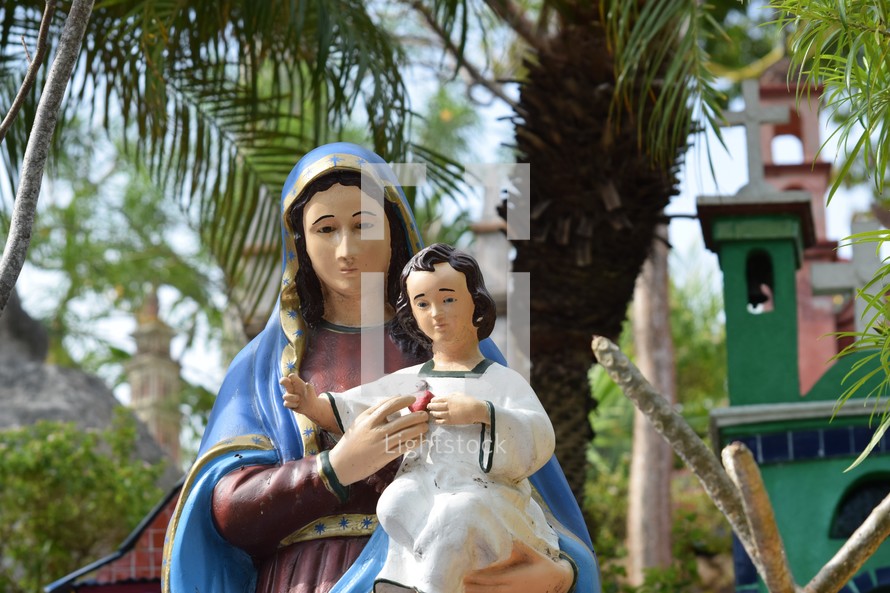 A statue of Mary holding baby Jesus in a colorful Mexican Cemetery 