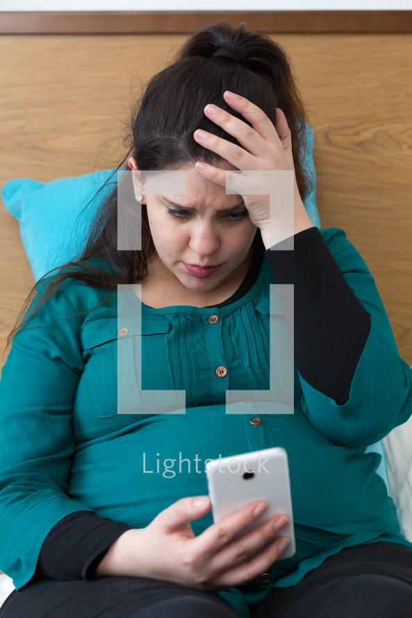 a pregnant woman looking at a cellphone 