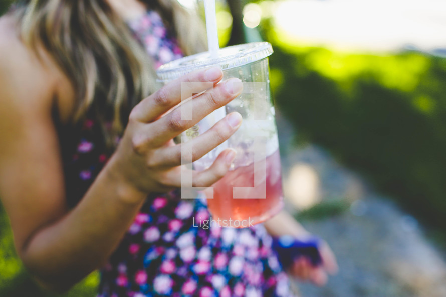 teen girl holding a plastic cup with straw