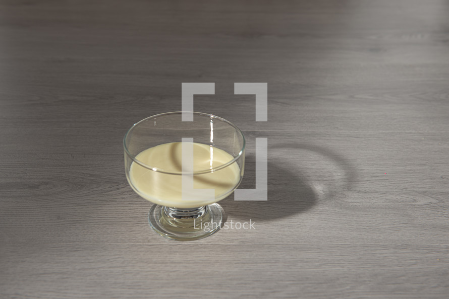 condensed milk in a transparent glass bowl on a wooden background