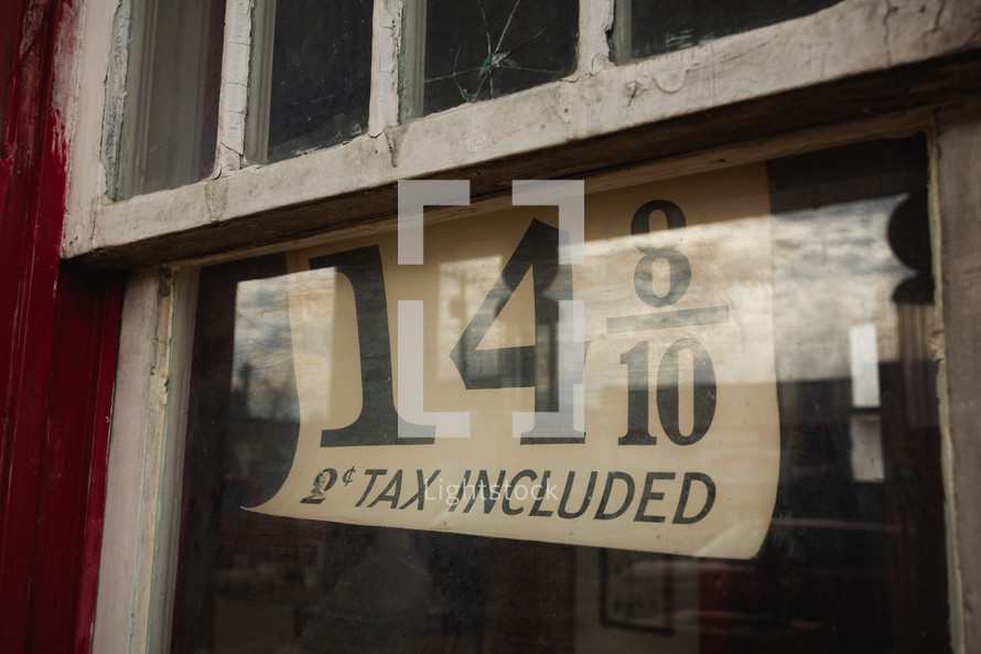 14 8/10 sign with 2 cent tax included - in small shop window