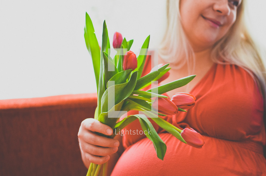a pregnant woman holding tulips 
