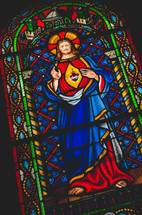A stained-glass window depicting Jesus and the sacred heart symbol