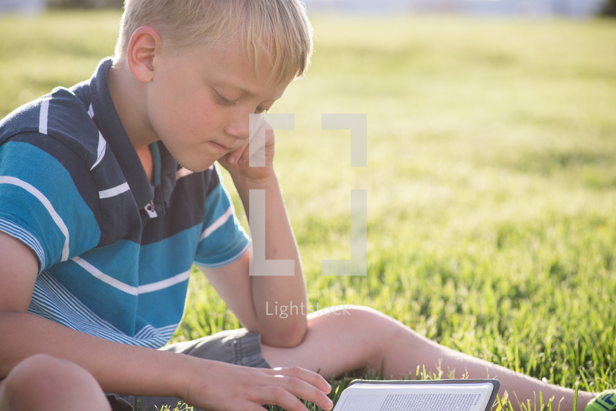 a child reading a Bible in the grass 
